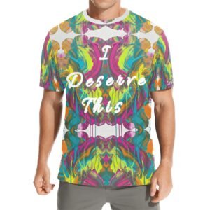 Unisex t‑shirt with vibrant, symmetrical abstract artwork in pink, green, yellow, orange, and blue, featuring the white cursive affirmation ‘I Deserve This’ across the chest. White bands at neckline and hem create a light, balanced frame.